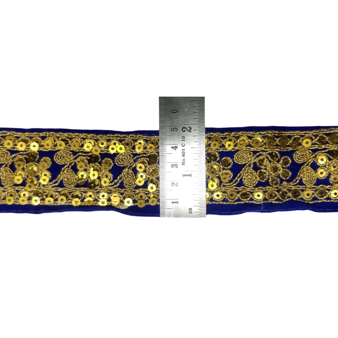 Navy blue ribbon with gold embroidery and a ruler for scale on a white background