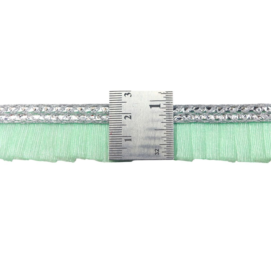 Close-up of a green fabric strip with silver trim and a ruler for scale on a white background