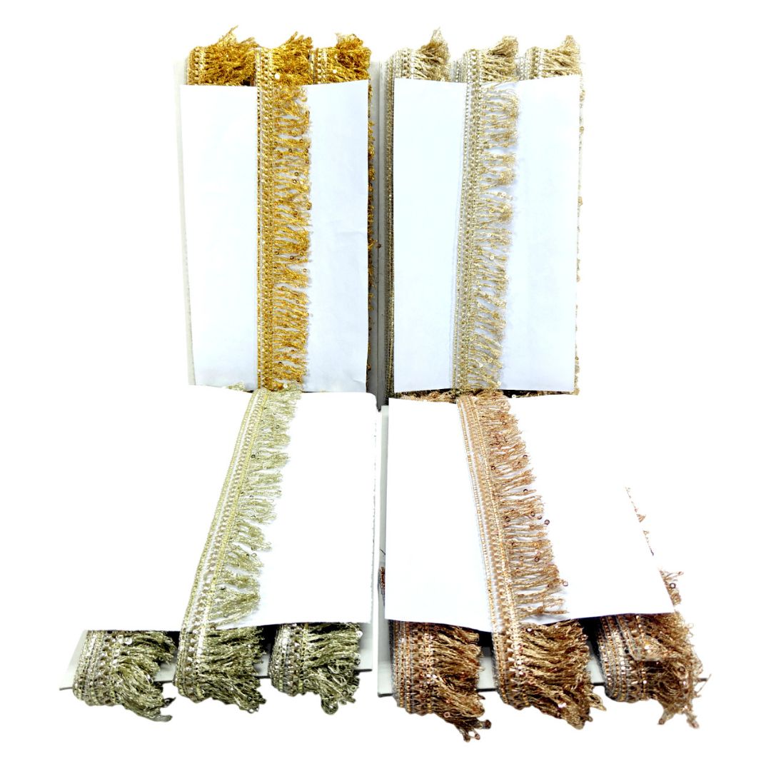 Set of four white napkins with gold, green, and brown fringes on a white background