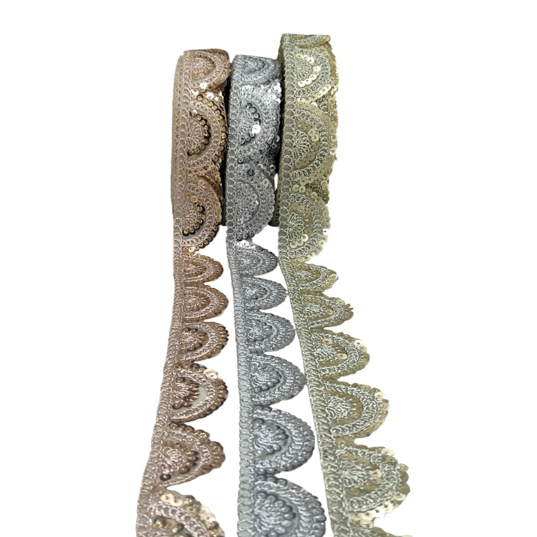 Three rolls of decorative lace ribbon in gold, silver, and bronze on a white background