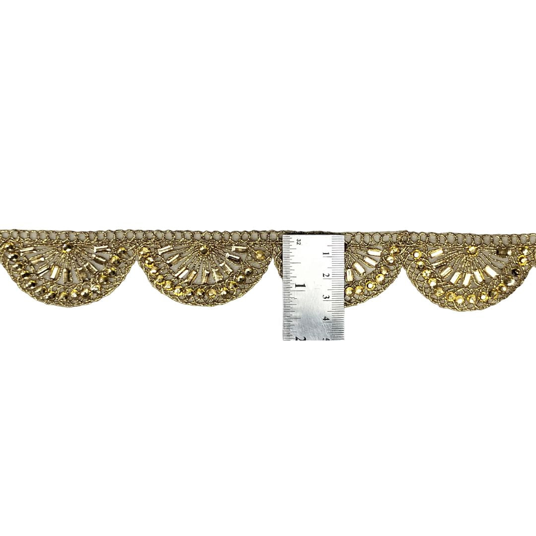 Decorative gold fabric trim with a ruler for scale on a white background