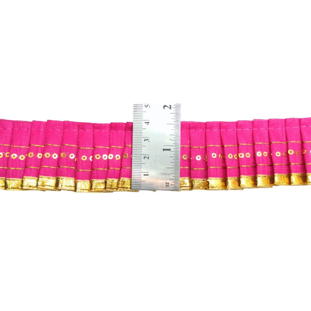 Pink fabric strip with gold border and a ruler for measurement on a white background