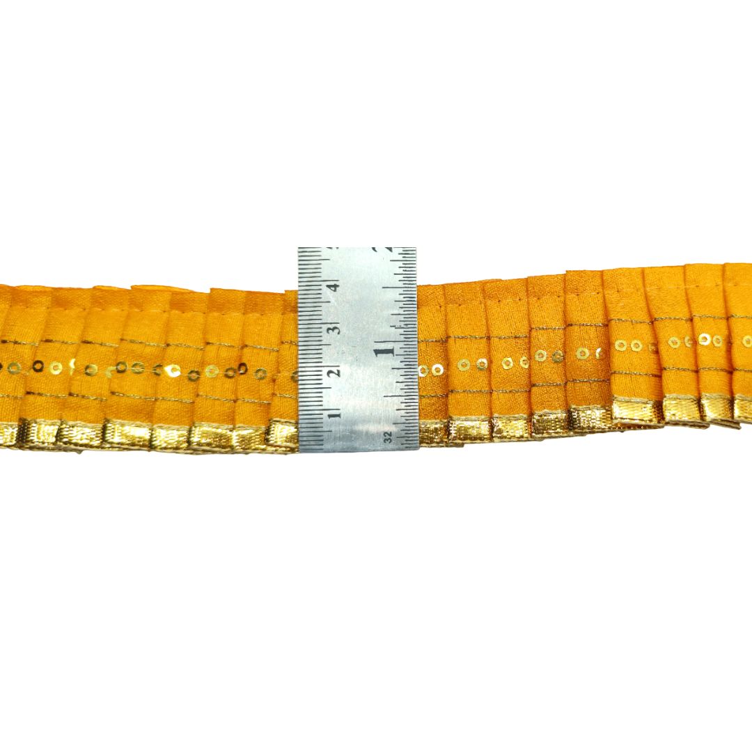 Yellow decorative ribbon with gold trim and a ruler for scale on a white background