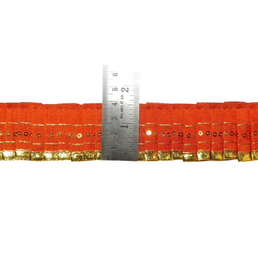 Orange fabric with gold trim and a ruler for scale on a white background