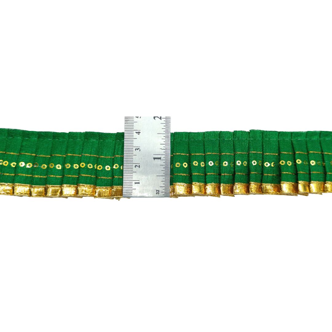 Green fabric with gold trim and a ruler for scale on a white background