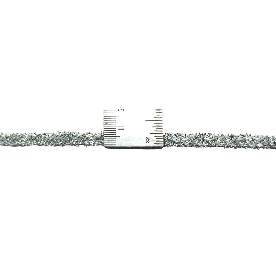 Thin silver chain with a ruler for scale on a white background