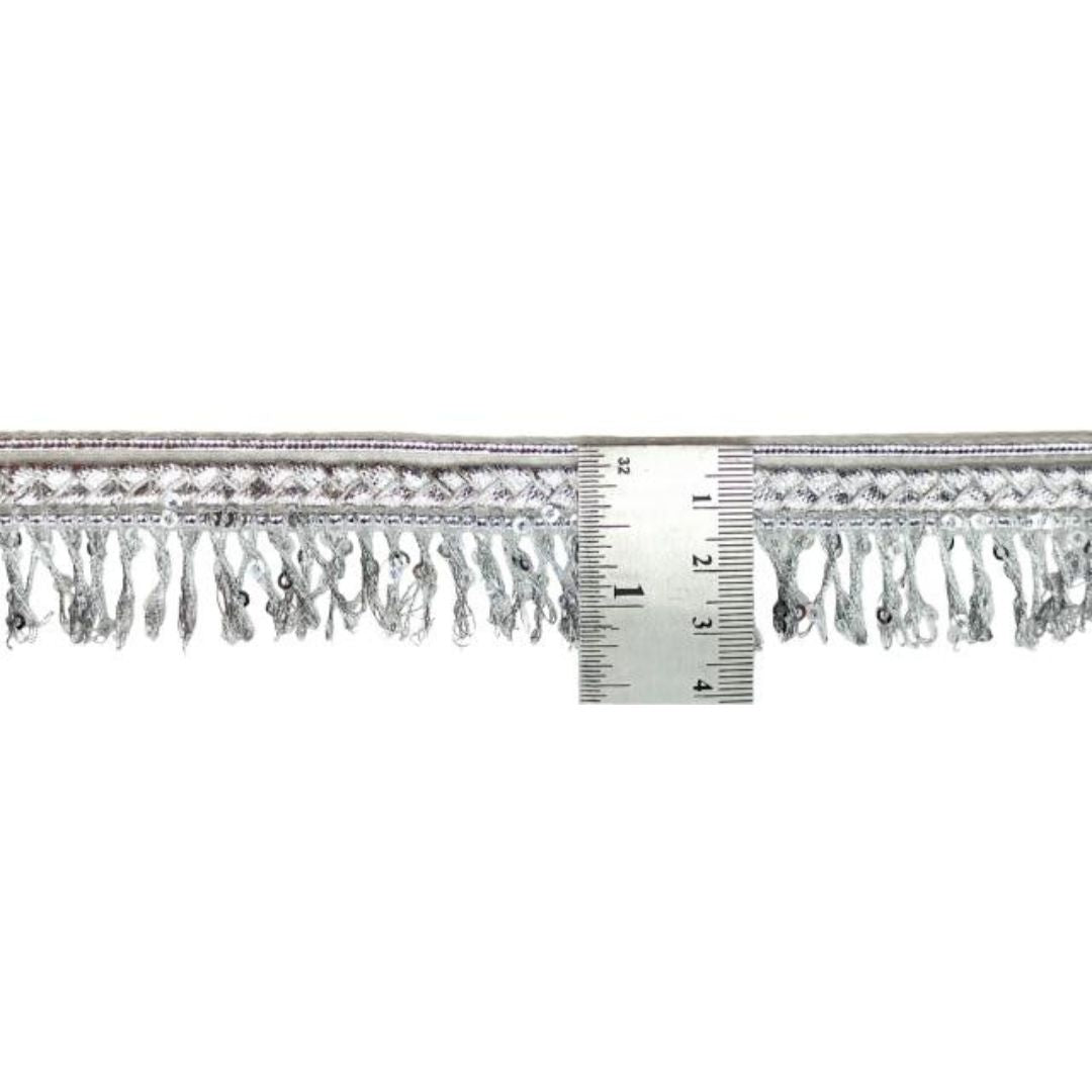 Decorative trim with fringe and a ruler for scale on a white background
