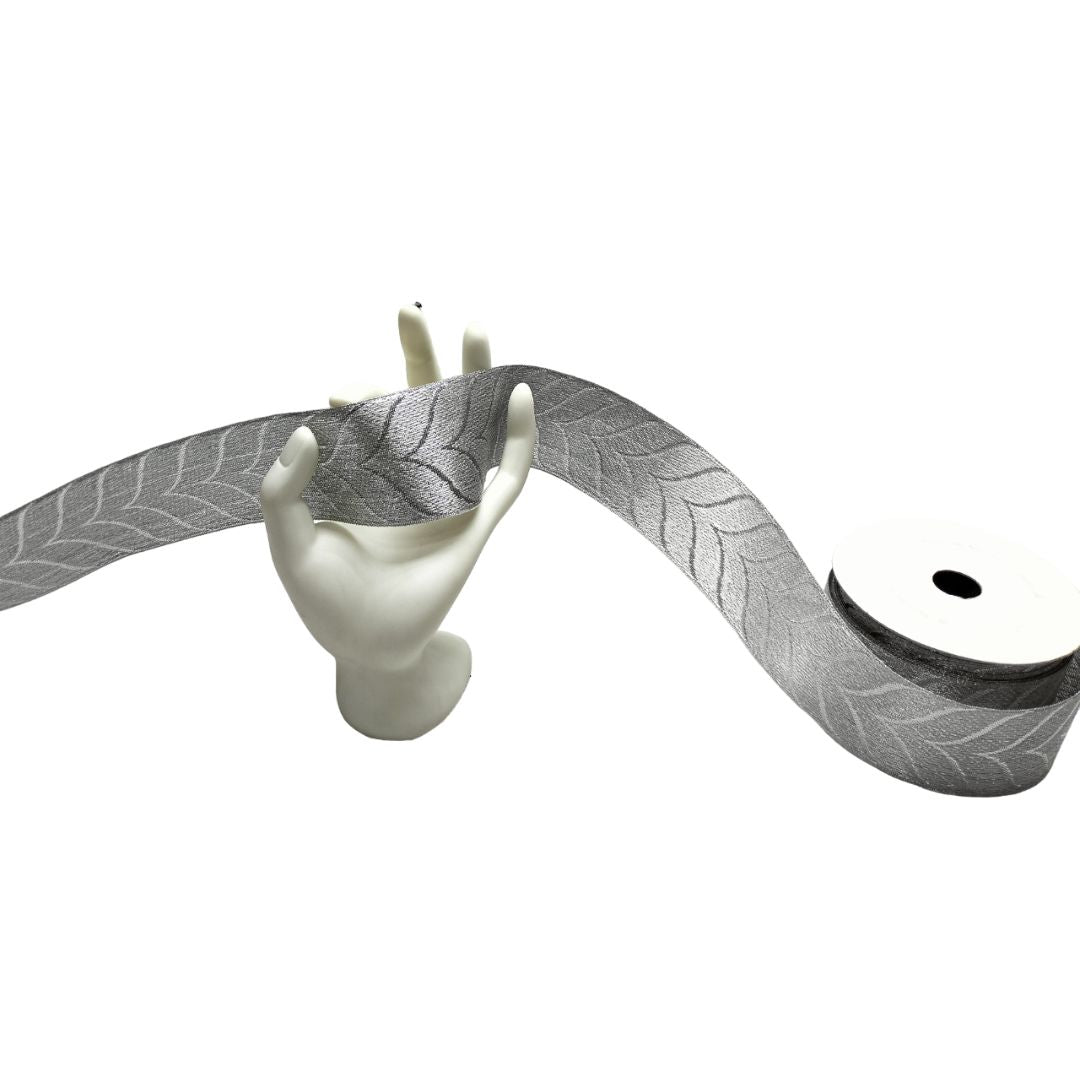 Gray ribbon with leaf pattern draped over a white mannequin hand on a white background