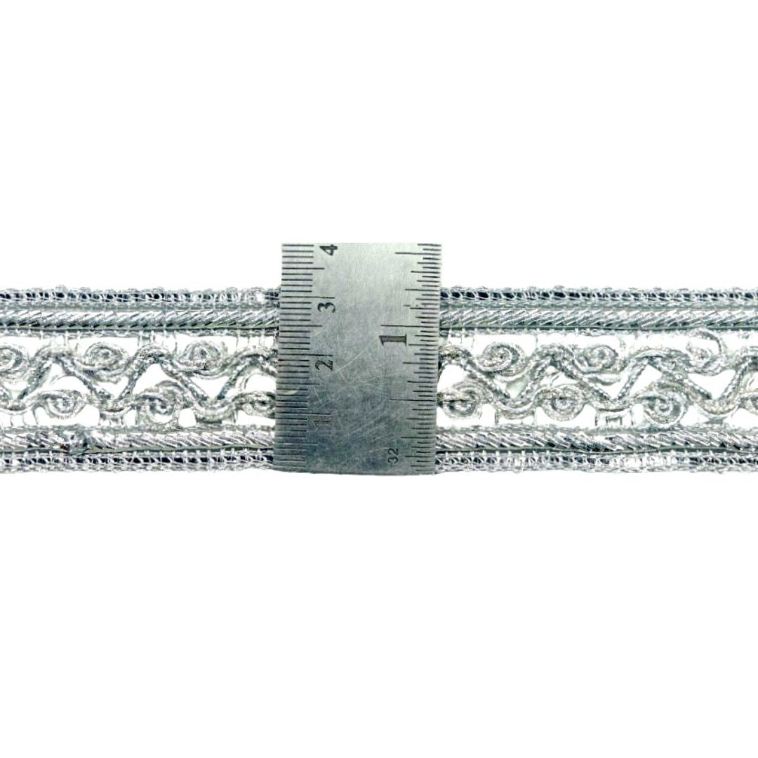 Decorative silver lace trim with a ruler for scale on a white background
