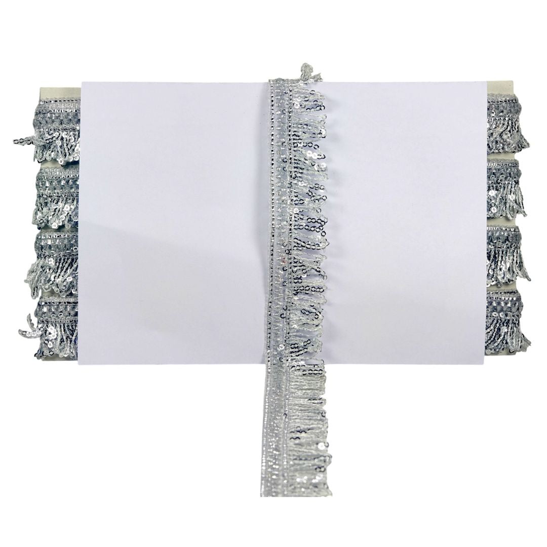 White pillow with silver fringe on a white background