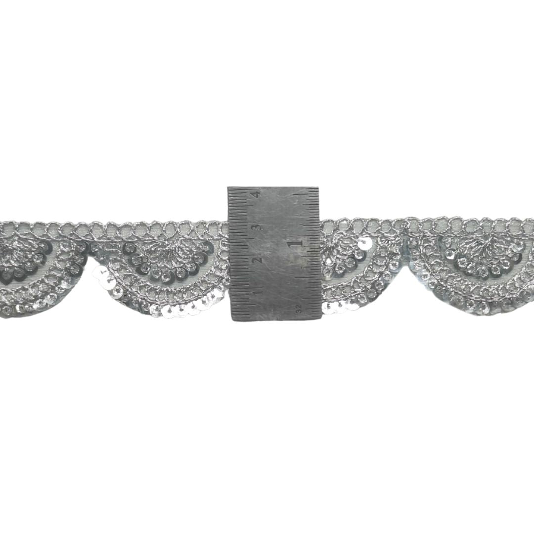 Decorative lace trim with a ruler for scale on a white background