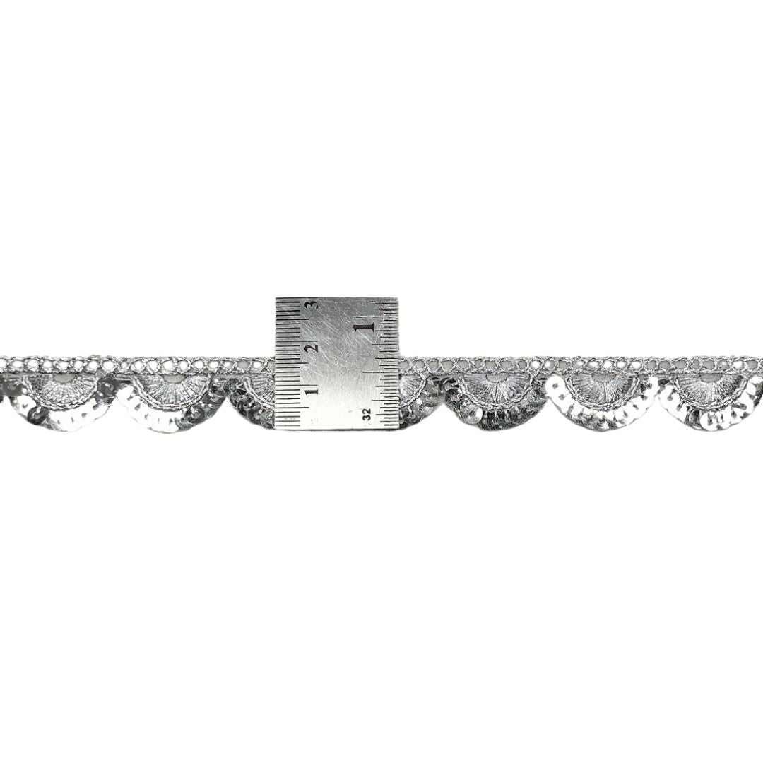 Decorative lace trim with a ruler for scale on a white background