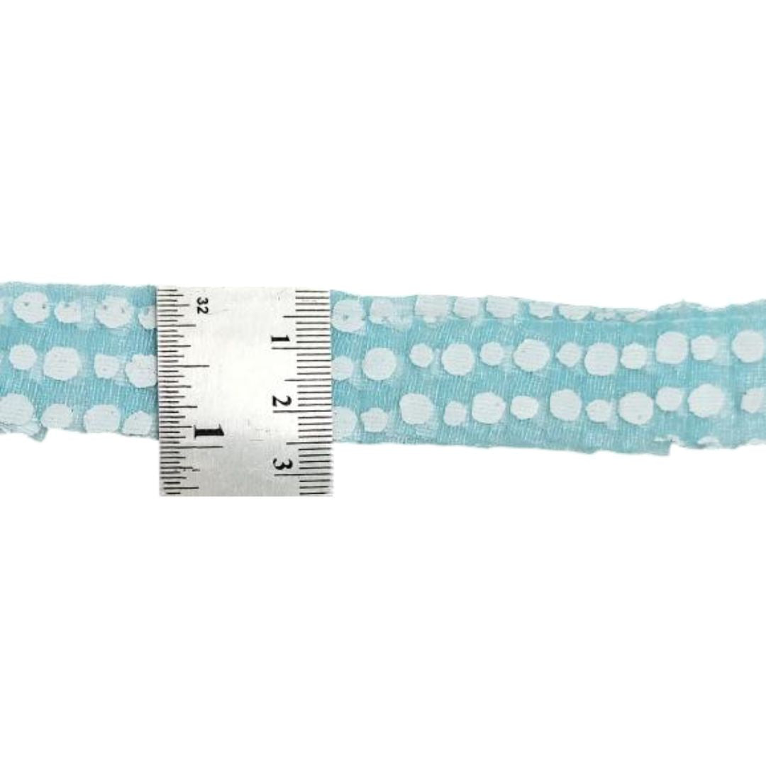 Light blue fabric with white polka dots and a ruler for scale on a white background