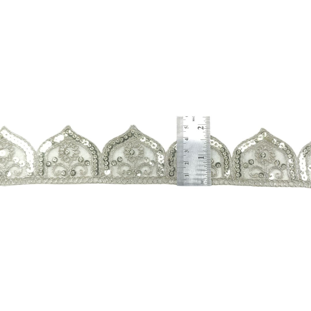 Decorative lace trim with a ruler for scale on a white background