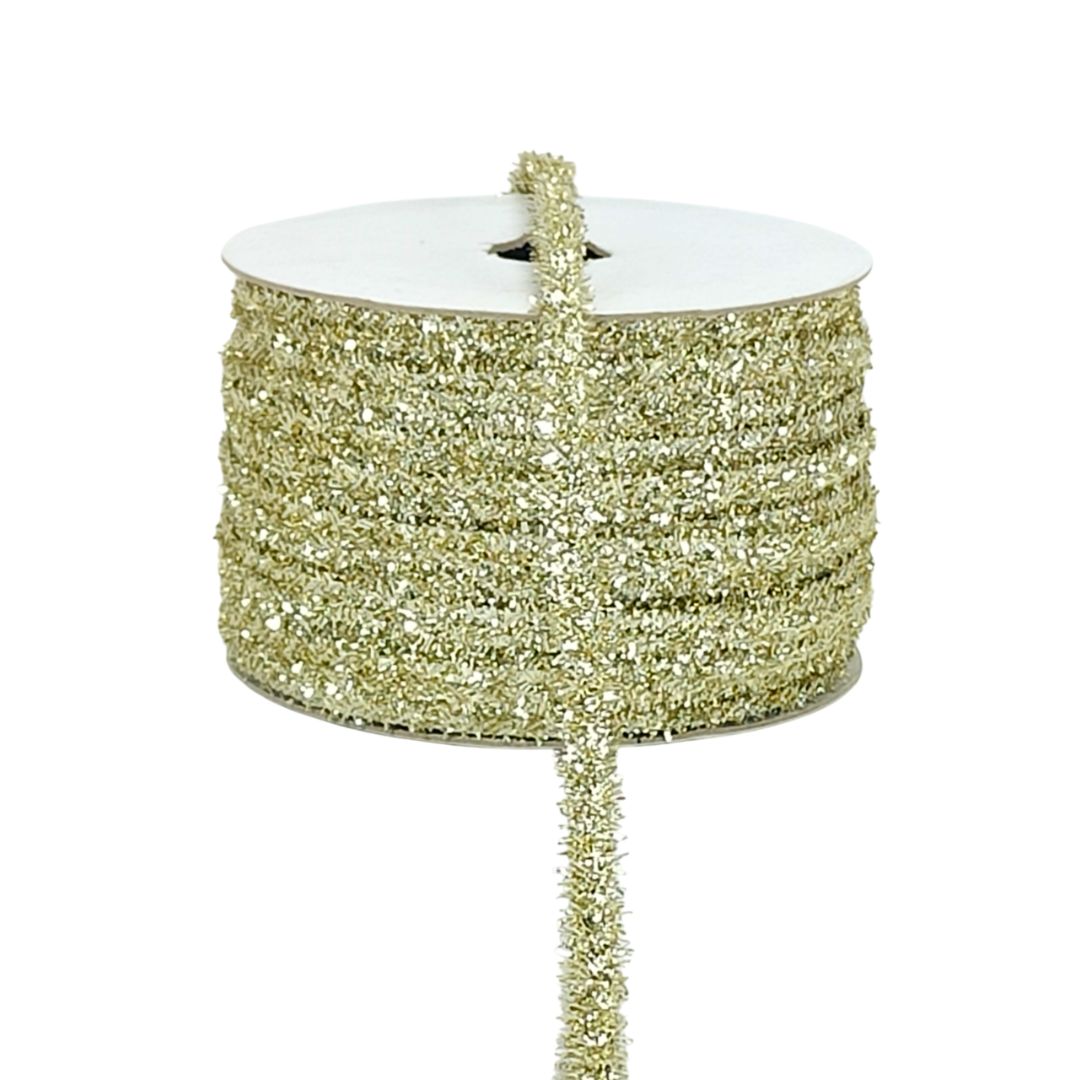 Gold glitter ribbon on a white spool against a white background