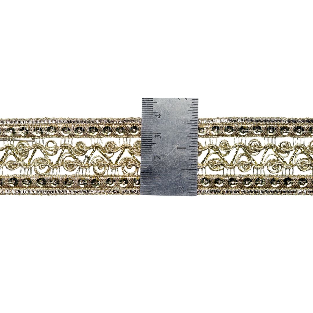 Decorative gold lace trim with a ruler for scale on a white background