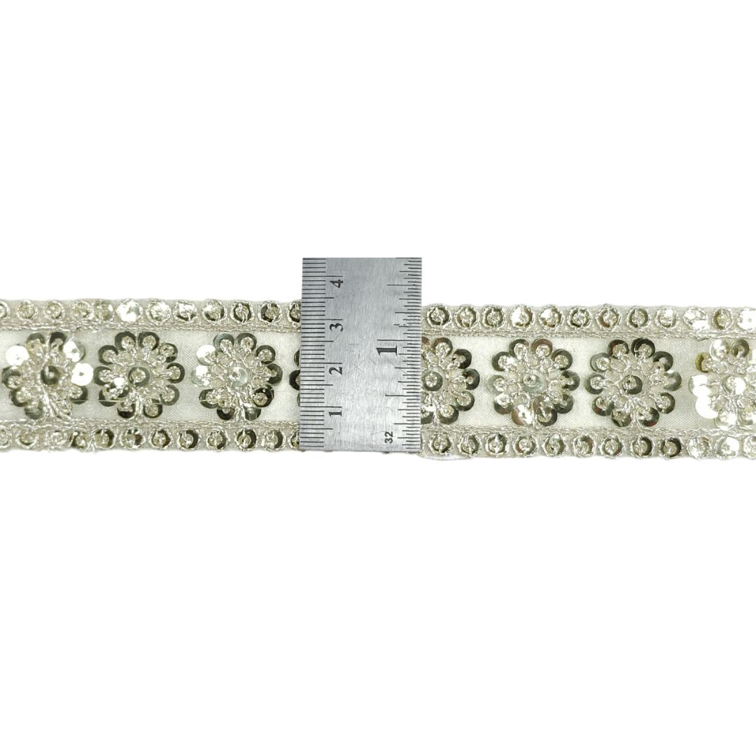 Decorative ribbon with floral patterns and a ruler for scale on a white background