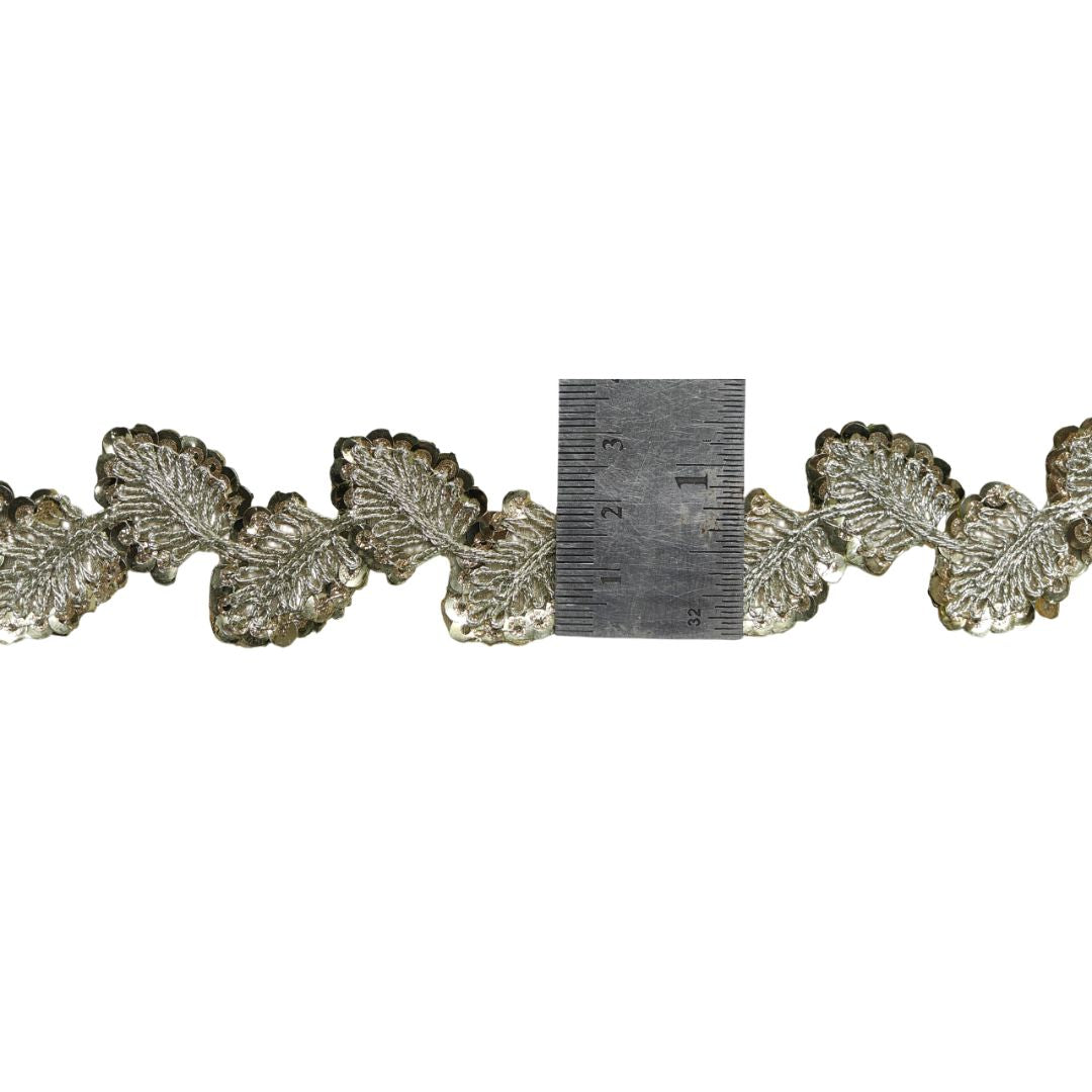 Decorative metallic leaf pattern with a ruler for scale on a white background