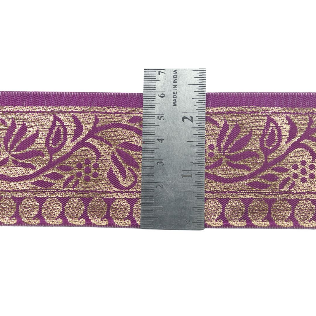 Purple and gold floral patterned ribbon with a ruler for scale on a white background