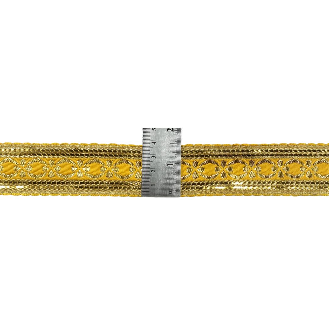 Gold lace trim with a ruler for scale on a white background