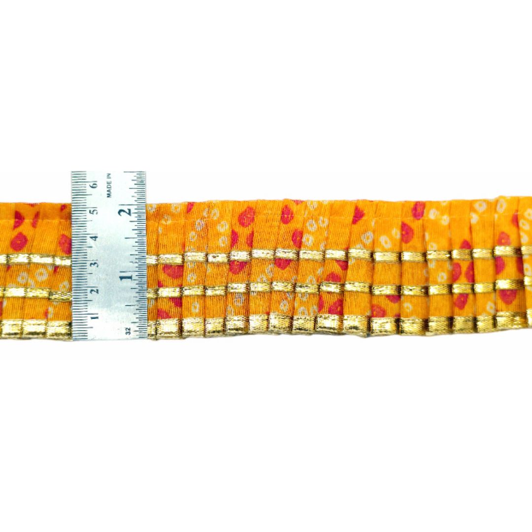 Strip of orange fabric with red and gold patterns, measured against a ruler on a white background.