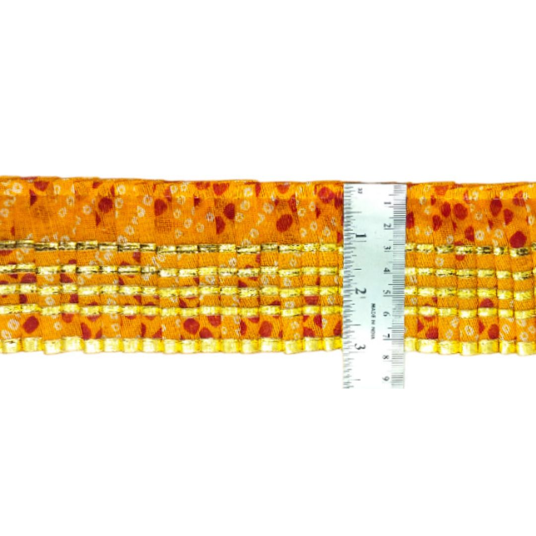 Strip of orange fabric with a pattern next to a ruler on a white background