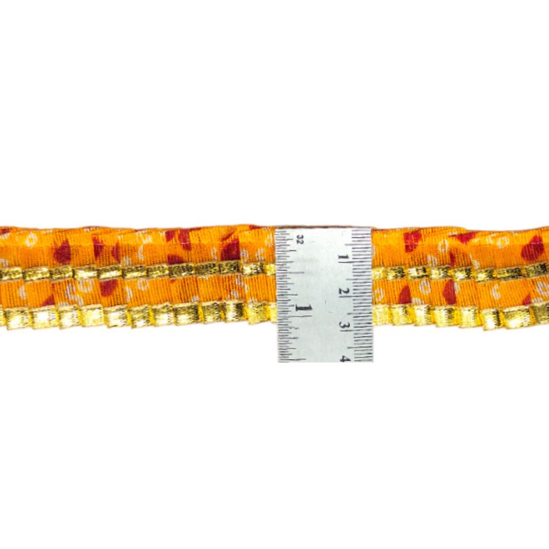 Orange fabric with gold trim and a ruler for scale on a white background