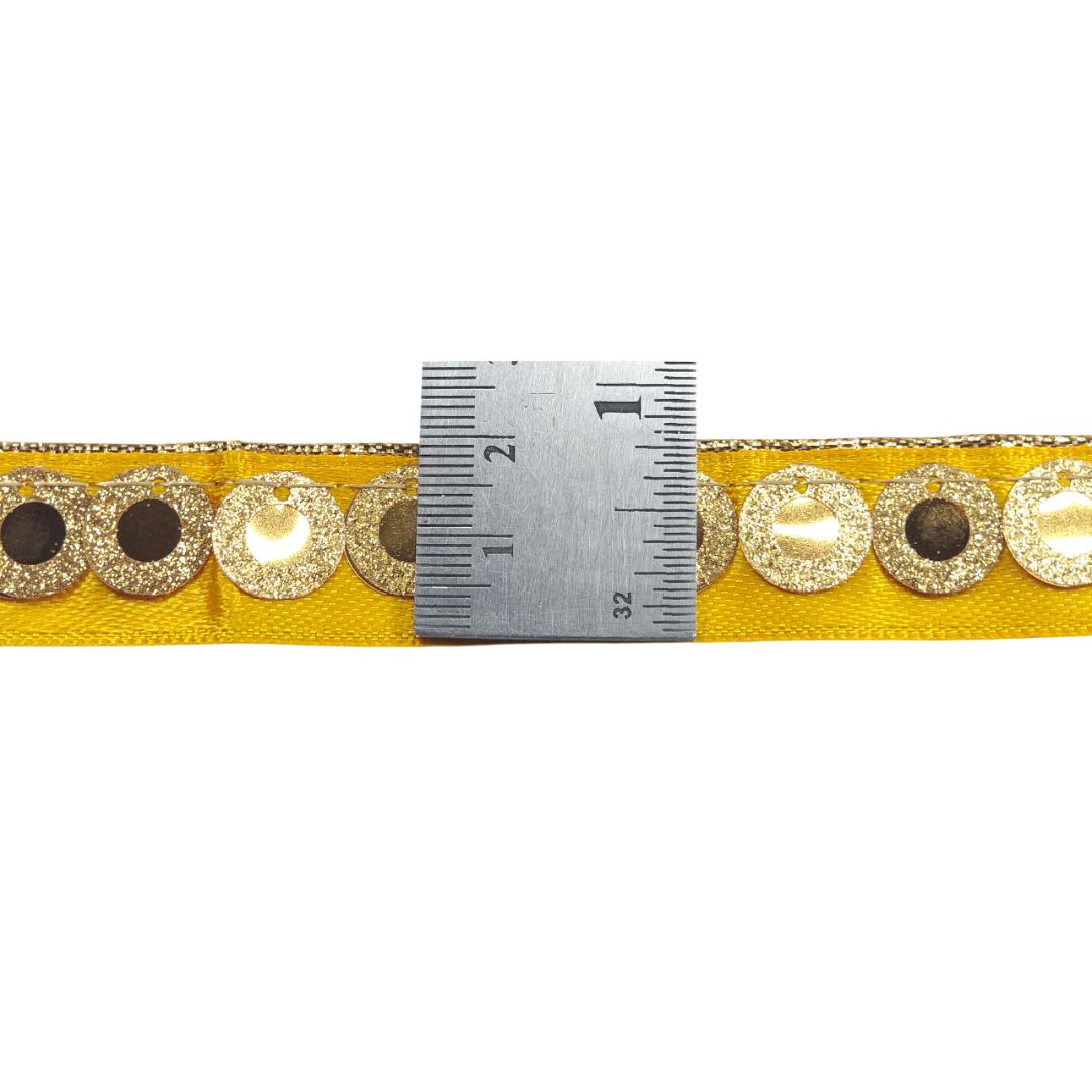 Yellow ribbon with decorative buttons and a ruler for measurement on a white background