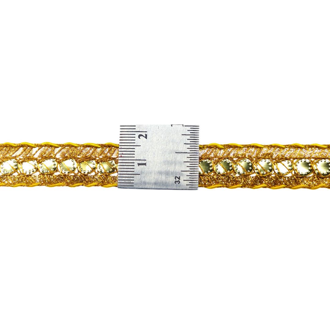 Gold bracelet with embedded stones and a ruler for size reference on a white background