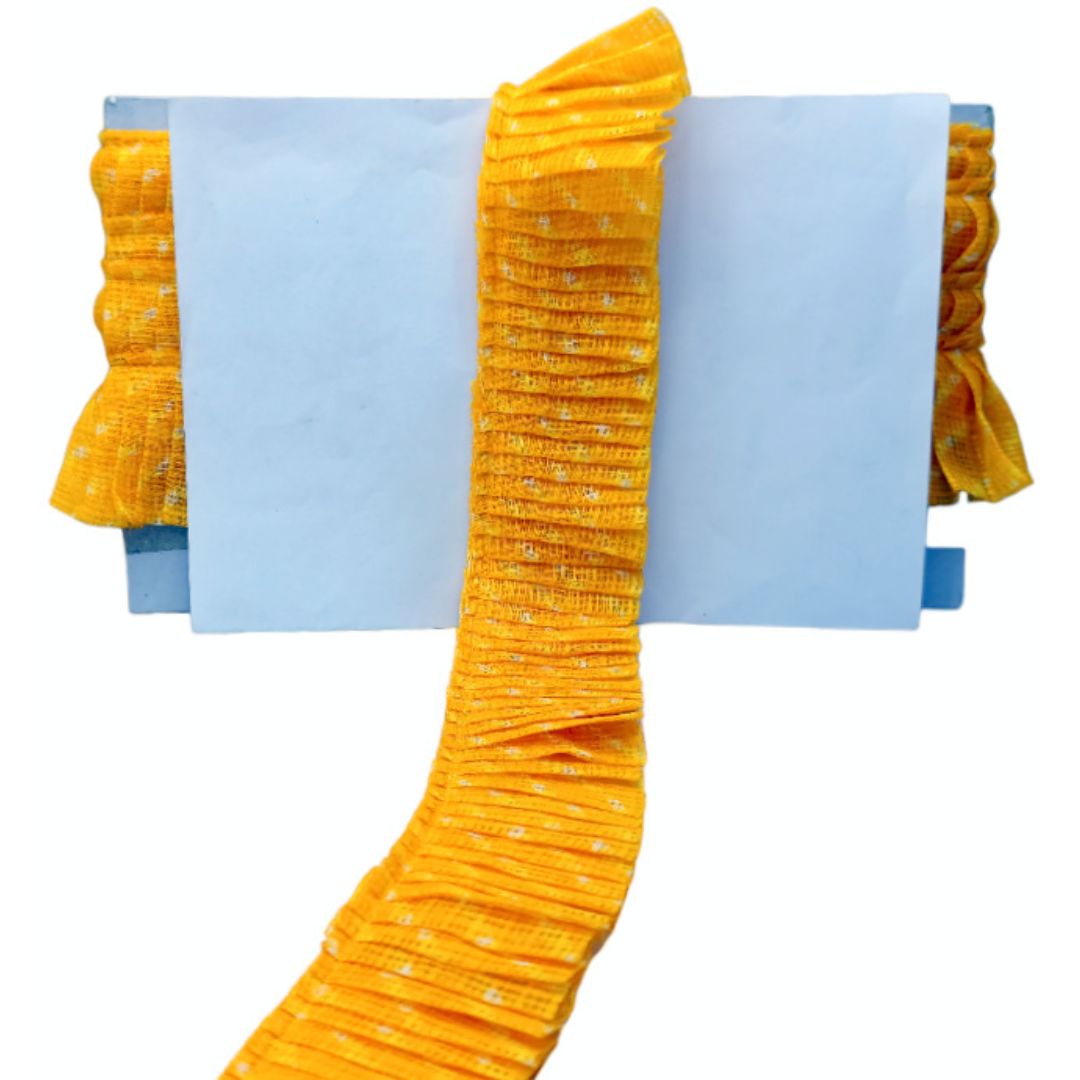 Yellow pleated fabric with blue paper underneath on a white background
