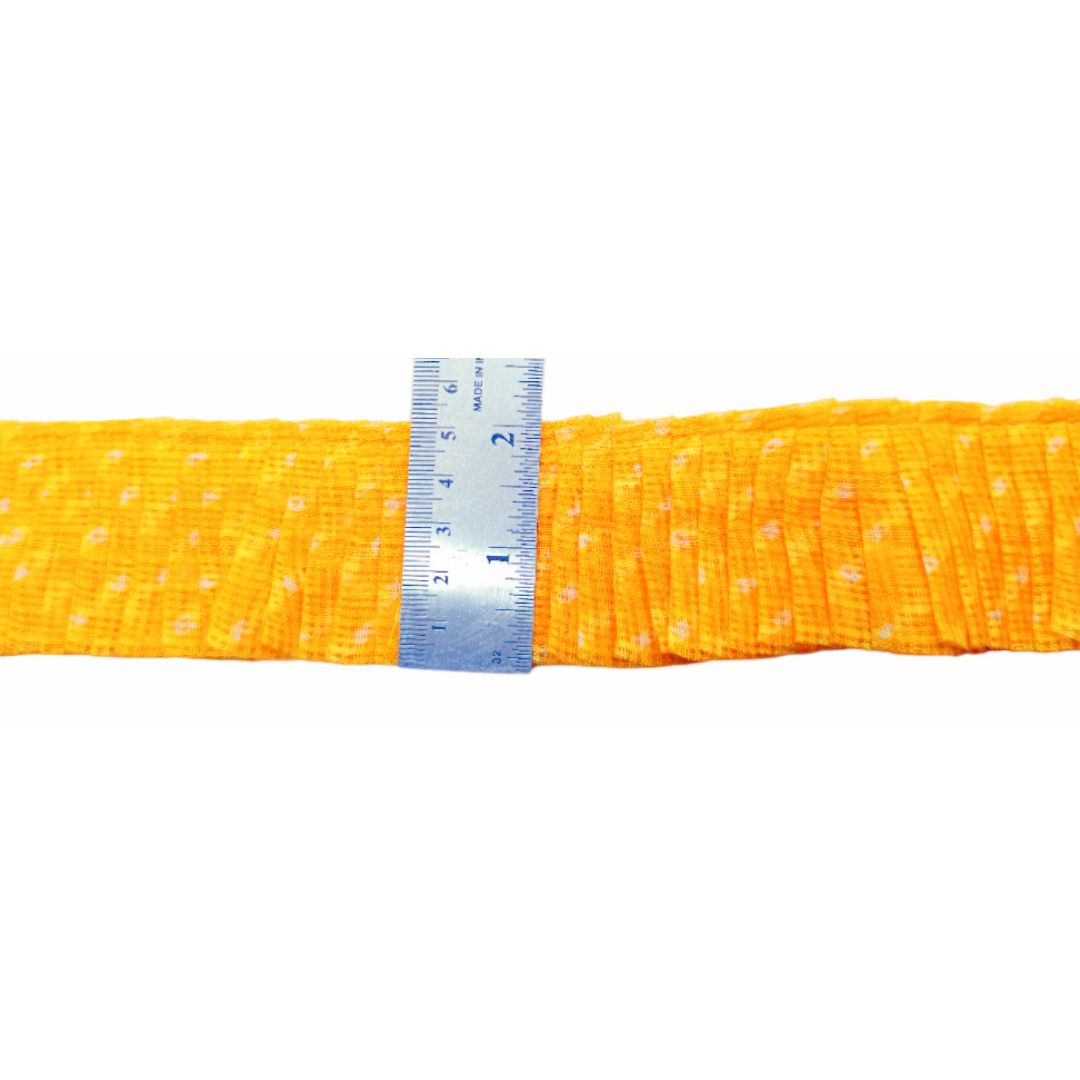 Yellow fabric with white polka dots and a ruler for scale on a white background