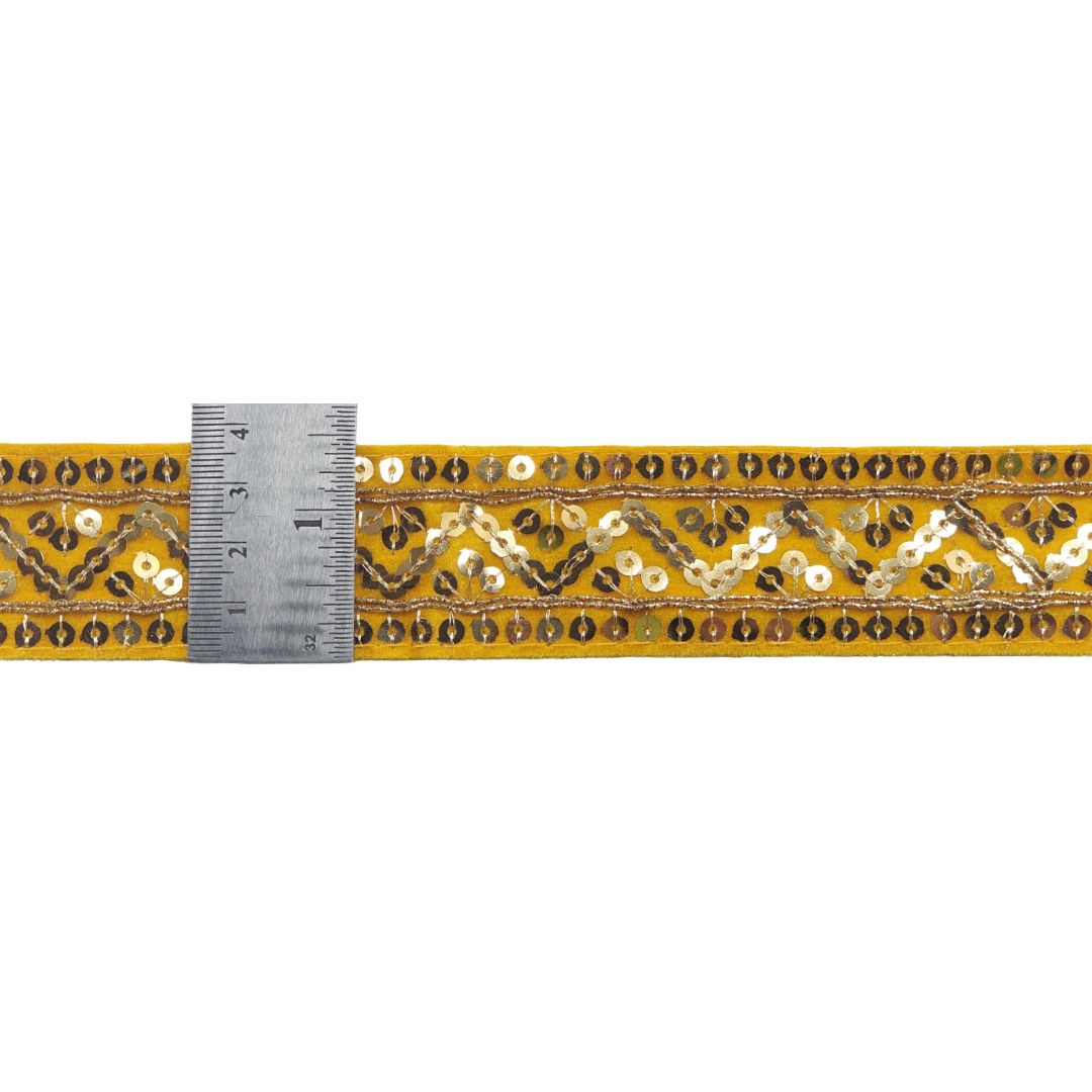 Decorative ribbon with gold and black pattern and a ruler for scale on a white background