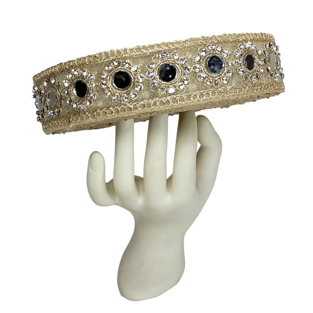 Decorative headband with crystals and stones on a mannequin hand against a white background
