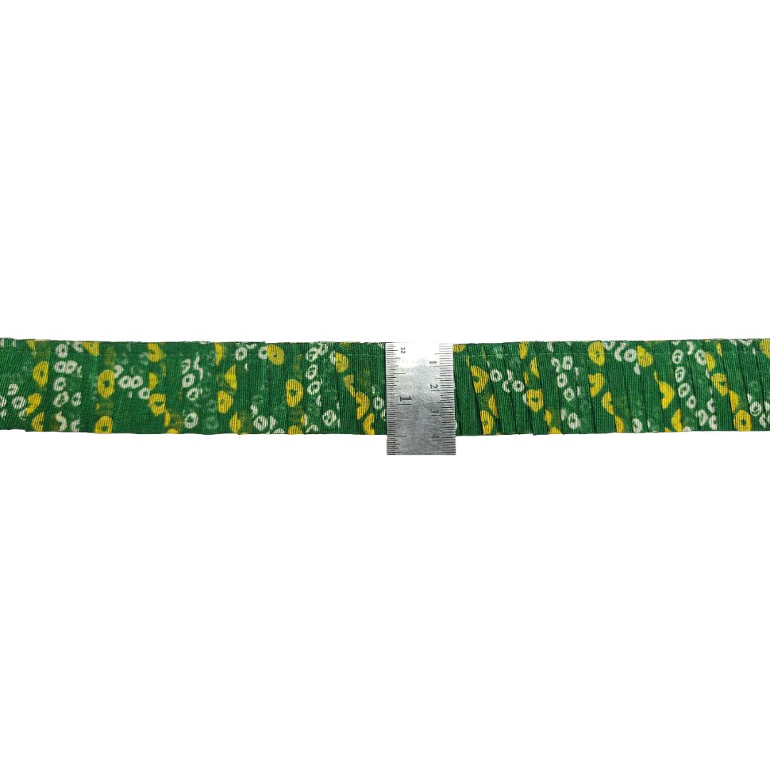 Green belt with yellow floral pattern and a metal ruler for scale on a white background
