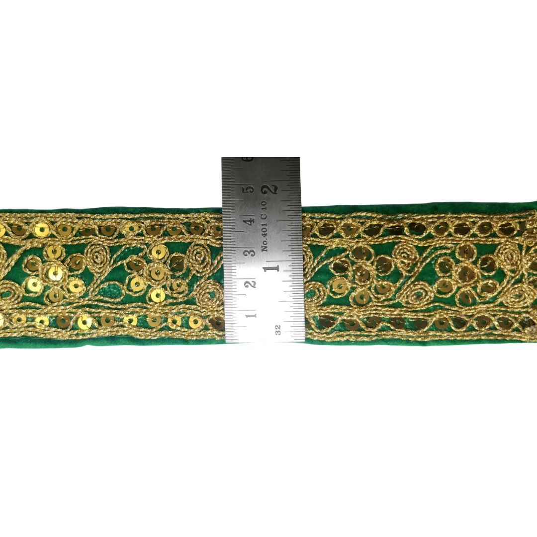 Green lace trim with gold embroidery and a ruler for scale on a white background