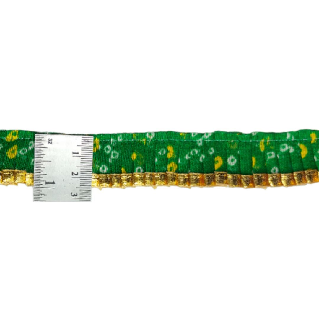 Green ribbon with gold accents and a measuring tape for scale on a white background
