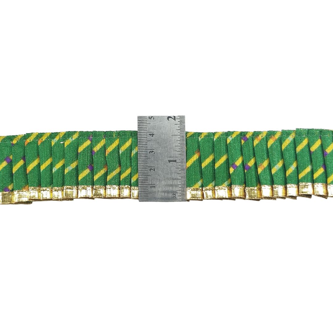 Green and gold striped ribbons with a ruler for scale on a white background