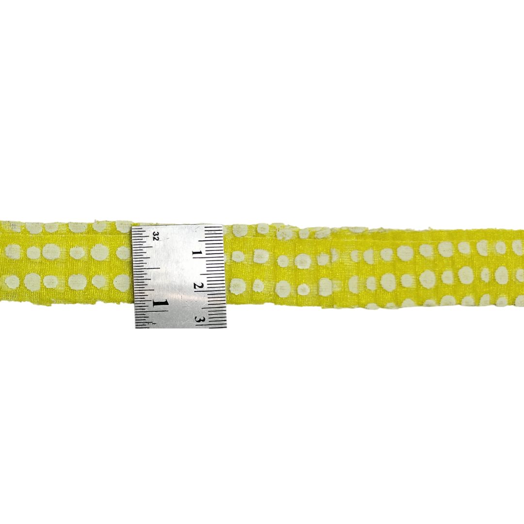 Yellow ribbon with white polka dots and a ruler for scale on a white background