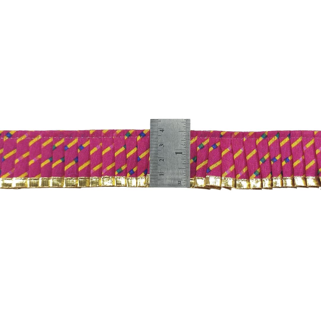 Decorative ribbon with colorful pattern and gold trim, measured against a ruler on a white background.