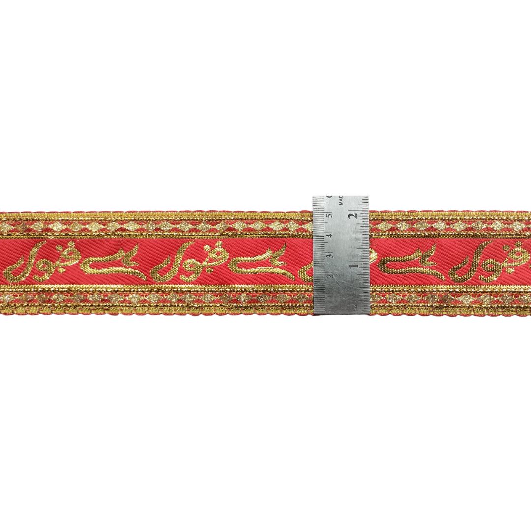 Red ribbon with gold embroidery and a ruler for scale on a white background