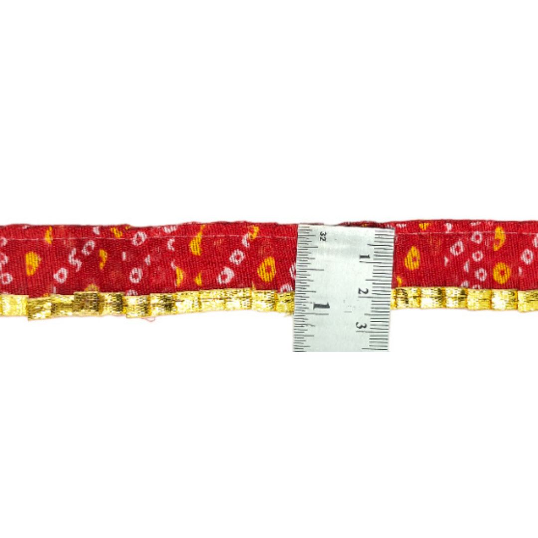 Red belt with gold and white pattern and a ruler for size reference on a white background