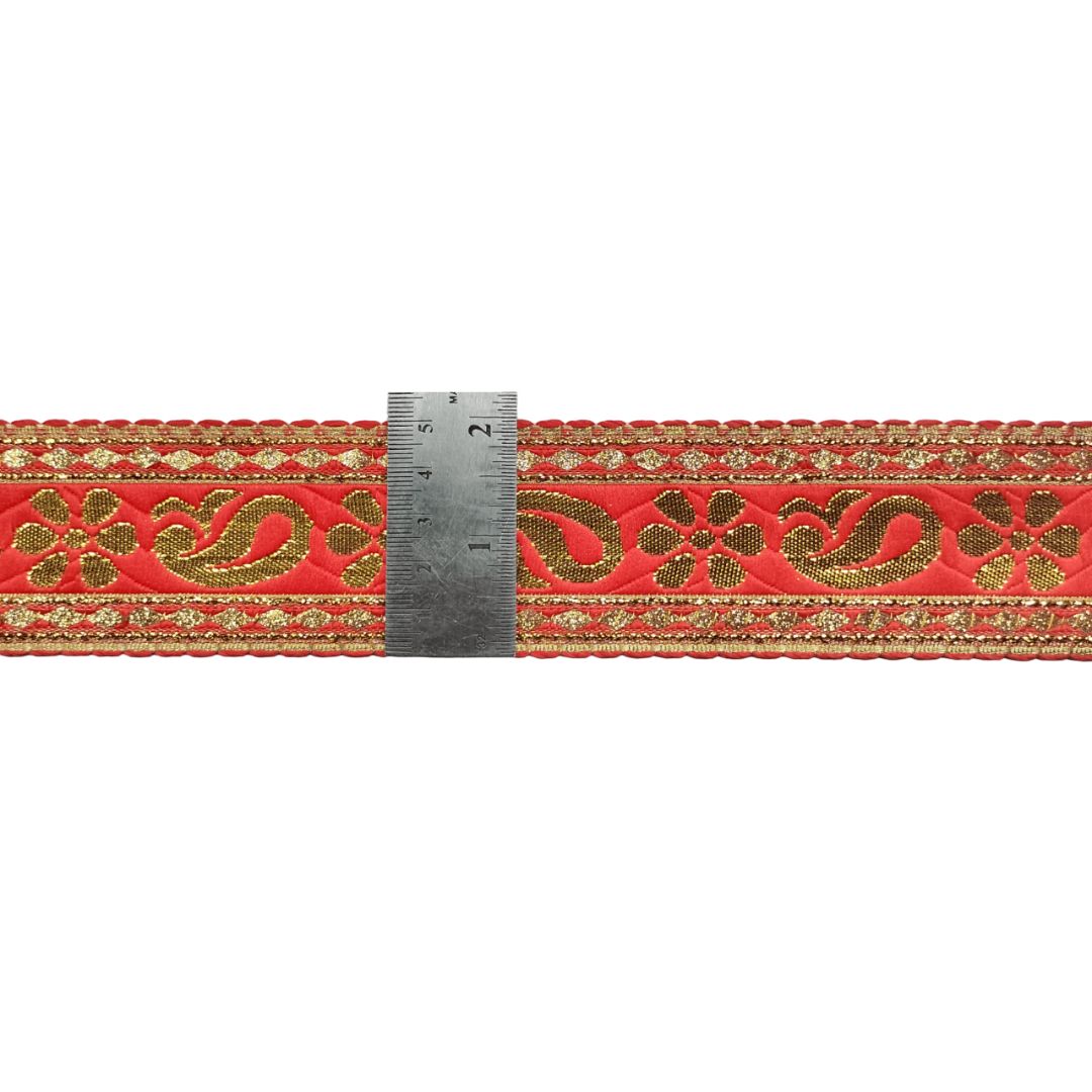 Decorative red ribbon with gold patterns and a ruler for scale on a white background