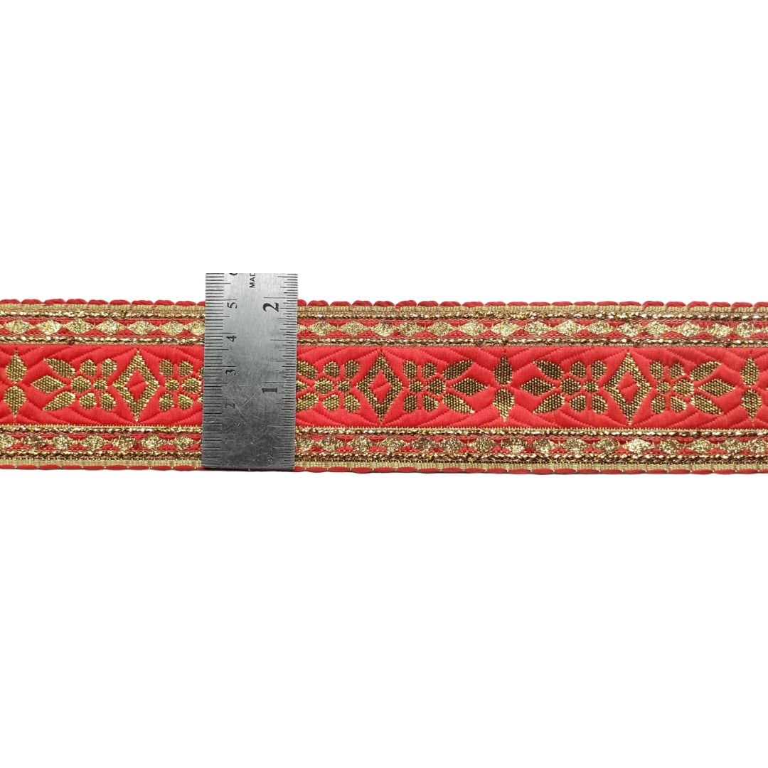 Red fabric strip with gold embroidery and a ruler for scale on a white background