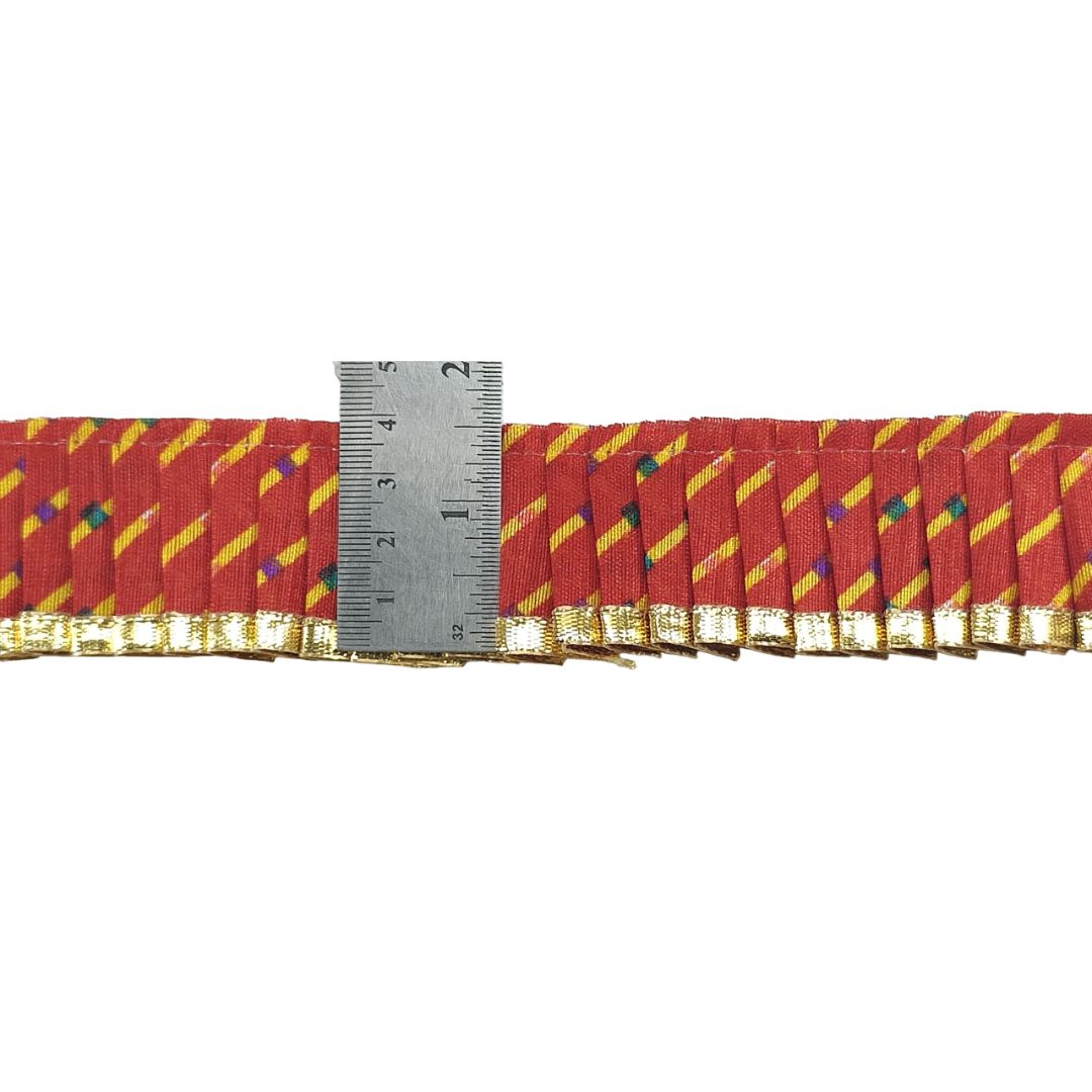 Red ribbon with yellow stripes and multicolored dots, measured against a ruler on a white background