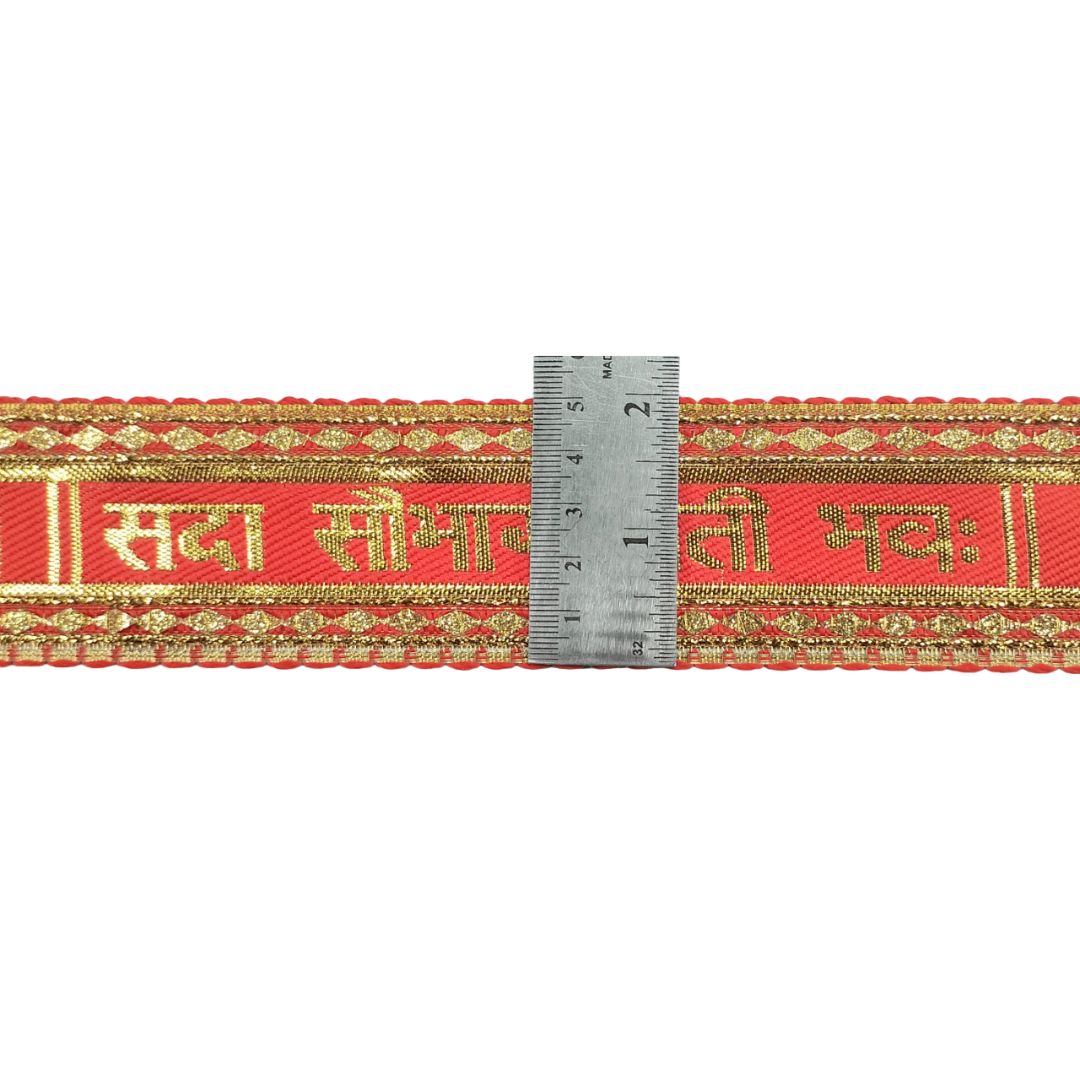 Red ribbon with gold text and patterns, measured against a ruler on a white background