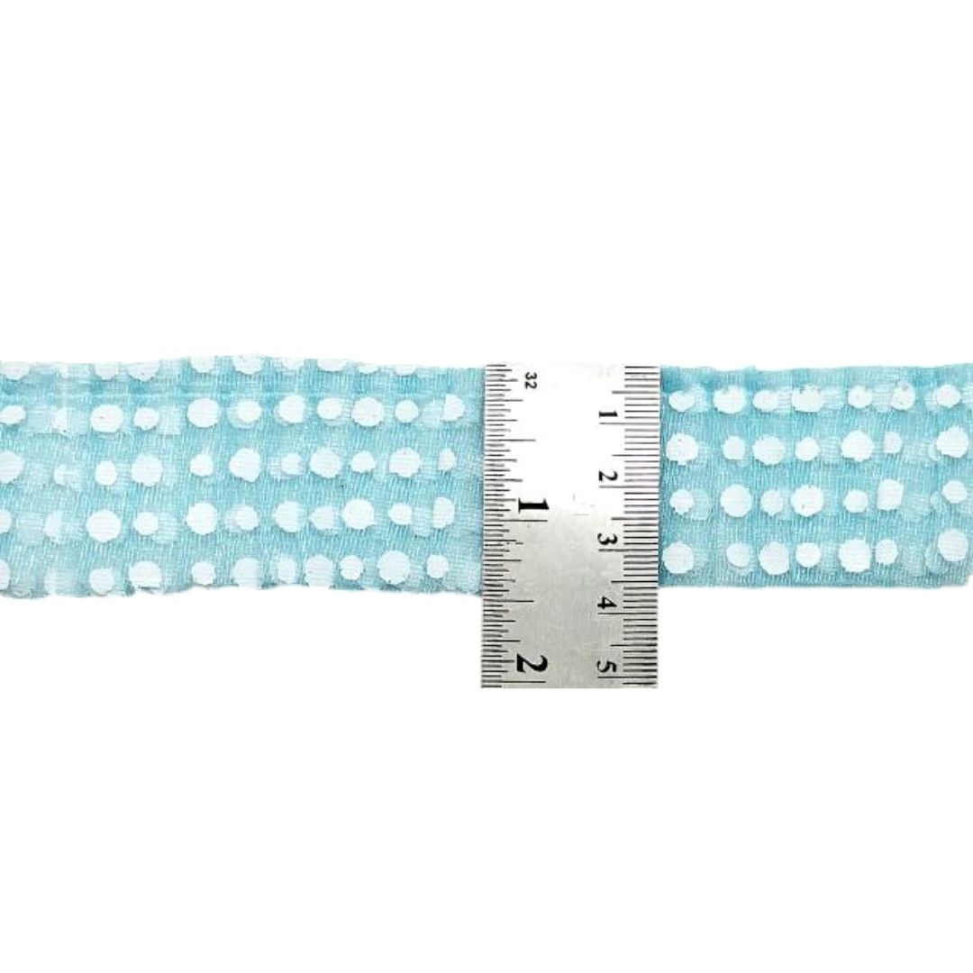 Fabric with white polka dots on a light blue background, measured by a ruler.