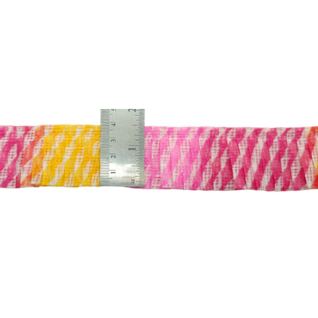 Strip of fabric with pink and yellow zebra pattern next to a ruler on a white background
